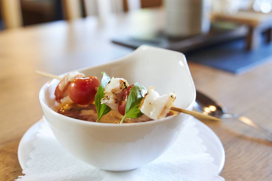 Appealingly arranged soup with a scampi tomato skewer